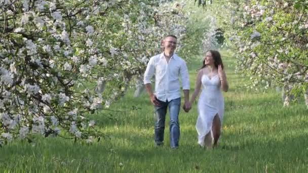 Молодой парень и девушка в цветущих яблонях в саду — стоковое видео