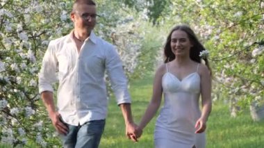 Genç adam ve kız bahçede çiçek açan elma ağaçlarında