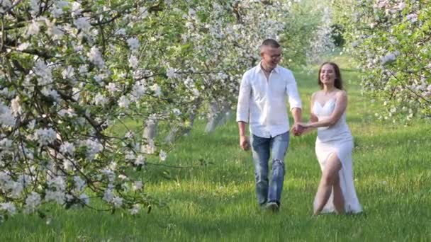 Joven chico y chica en flor de manzanos en el jardín — Vídeos de Stock