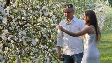 2020 bahçesindeki çiçek açan elma ağaçlarındaki genç adam ve kız.