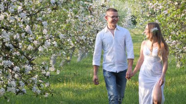 2020 bahçesindeki çiçek açan elma ağaçlarındaki genç adam ve kız.