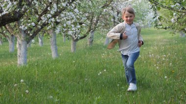2020 'de bahçede çimlerin üzerinde çiçek açan elma ağaçlarının yanında bir çocuk.