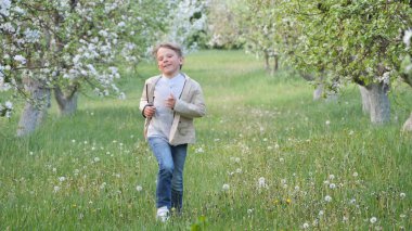 2020 'de bahçede çimlerin üzerinde çiçek açan elma ağaçlarının yanında bir çocuk.
