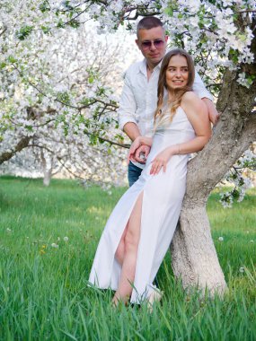 2020 bahçesindeki çiçek açan elma ağaçlarındaki genç adam ve kız.