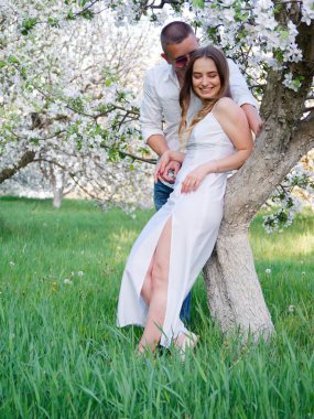 2020 bahçesindeki çiçek açan elma ağaçlarındaki genç adam ve kız.