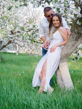 2020 bahçesindeki çiçek açan elma ağaçlarındaki genç adam ve kız.