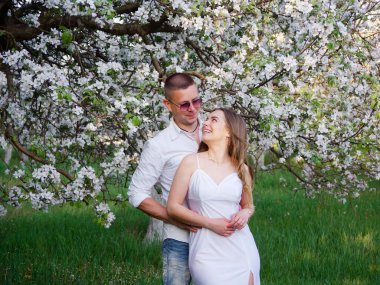 2020 bahçesindeki çiçek açan elma ağaçlarındaki genç adam ve kız.