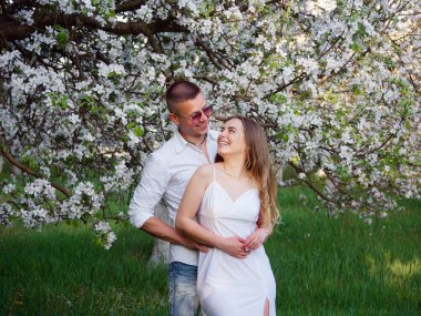 2020 bahçesindeki çiçek açan elma ağaçlarındaki genç adam ve kız.