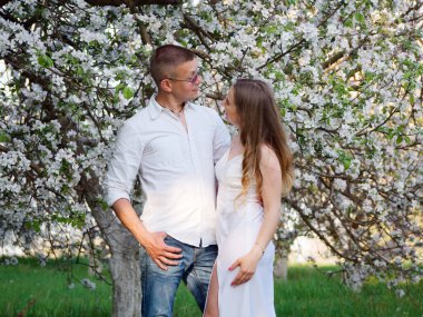 2020 bahçesindeki çiçek açan elma ağaçlarındaki genç adam ve kız.