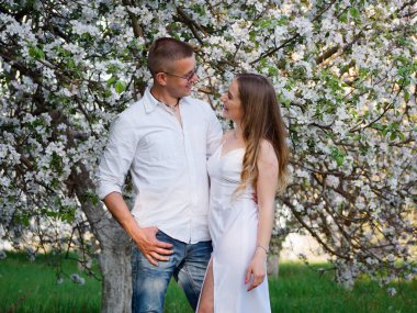 2020 bahçesindeki çiçek açan elma ağaçlarındaki genç adam ve kız.