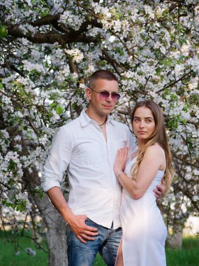 2020 bahçesindeki çiçek açan elma ağaçlarındaki genç adam ve kız.