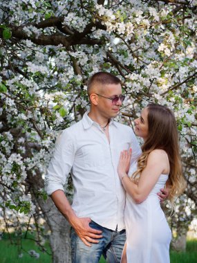 2020 bahçesindeki çiçek açan elma ağaçlarındaki genç adam ve kız.