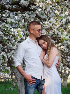 2020 bahçesindeki çiçek açan elma ağaçlarındaki genç adam ve kız.