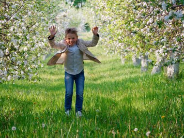 2020 'de bahçede çimlerin üzerinde çiçek açan elma ağaçlarının yanında bir çocuk.