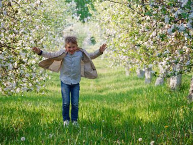 2020 'de bahçede çimlerin üzerinde çiçek açan elma ağaçlarının yanında bir çocuk.