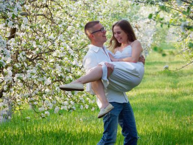 2020 bahçesindeki çiçek açan elma ağaçlarındaki genç adam ve kız.