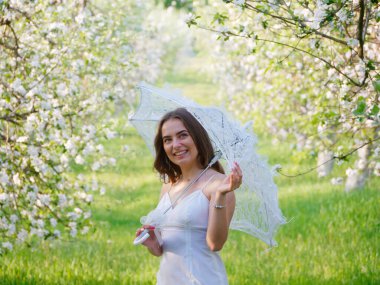 2020 bahçesinde çiçek açan elma ağaçlarında beyaz şemsiyeli bir kız.