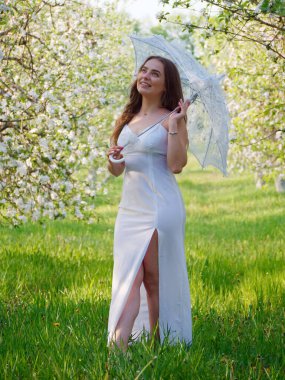 2020 bahçesinde çiçek açan elma ağaçlarında beyaz şemsiyeli bir kız.