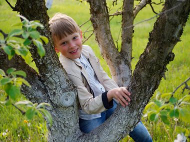 2020 'de bahçede çimlerin üzerinde çiçek açan elma ağaçlarının yanında bir çocuk.