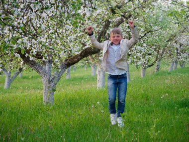 2020 'de bahçede çimlerin üzerinde çiçek açan elma ağaçlarının yanında bir çocuk.