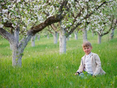 2020 'de bahçede çimlerin üzerinde çiçek açan elma ağaçlarının yanında bir çocuk.