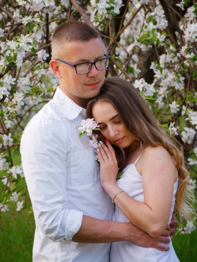 2020 bahçesindeki çiçek açan elma ağaçlarındaki genç adam ve kız.