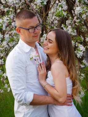 2020 bahçesindeki çiçek açan elma ağaçlarındaki genç adam ve kız.