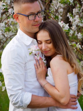 2020 bahçesindeki çiçek açan elma ağaçlarındaki genç adam ve kız.