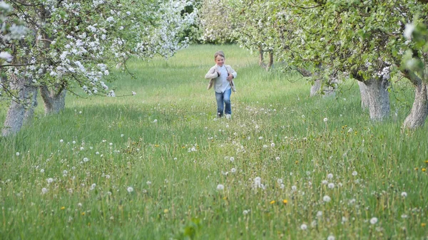 2020 'de bahçede çimlerin üzerinde çiçek açan elma ağaçlarının yanında bir çocuk.