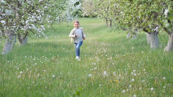 2020 'de bahçede çimlerin üzerinde çiçek açan elma ağaçlarının yanında bir çocuk.