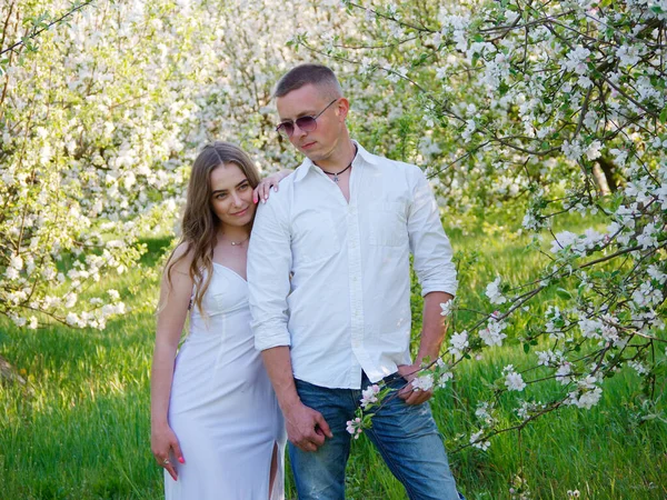 2020 bahçesindeki çiçek açan elma ağaçlarındaki genç adam ve kız.