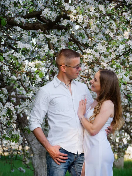 2020 bahçesindeki çiçek açan elma ağaçlarındaki genç adam ve kız.