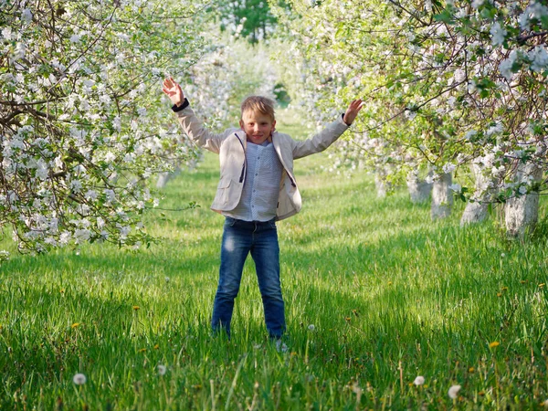 2020 'de bahçede çimlerin üzerinde çiçek açan elma ağaçlarının yanında bir çocuk.