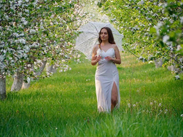 庭でリンゴの木を咲かせている白い傘の女の子2020 — ストック写真