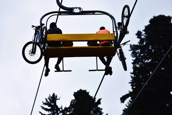 Mountain bikers on a chair lift in the mountain. — Stock Photo, Image