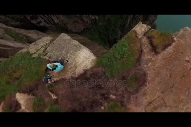 Norveç. Dağlar. Kız uçurumun kenarında oturuyor. Drone görüntülemek