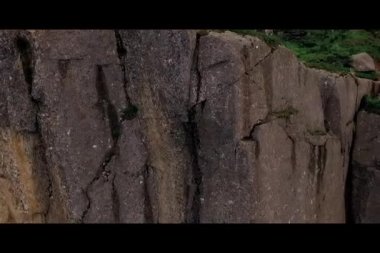 Norveç. Dağlar. Bir kız uçurumun kenarında oturur. Drone görüntülemek