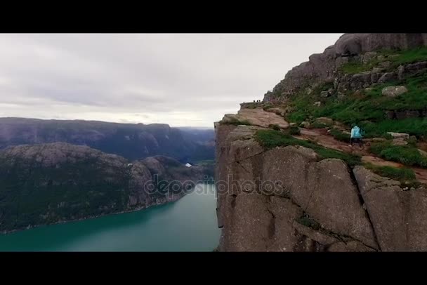 Norwegen. Mädchen sitzt am Rand der Klippe. Blick aus der Drohne — Stockvideo