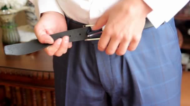 Мужчина пристегивает ремень к брюкам — стоковое видео