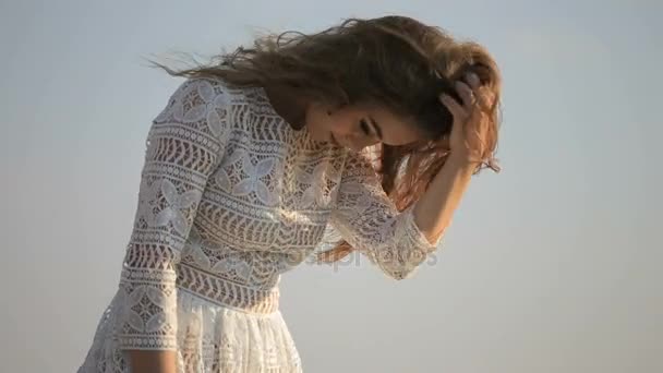 Retrato de una hermosa chica sobre un fondo azul del cielo — Vídeos de Stock