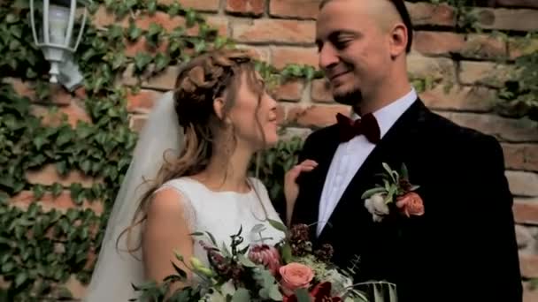 Belos recém-casados casal contra um fundo de parede de tijolo — Vídeo de Stock