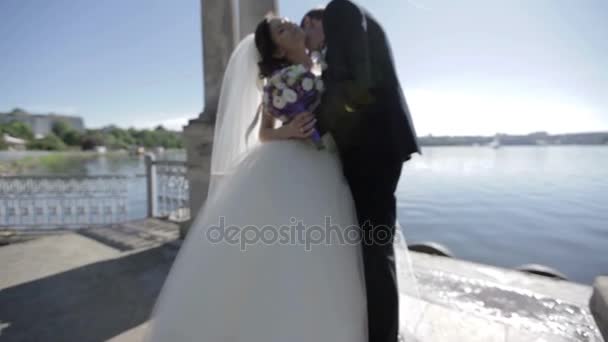 Brudgummen kyssa bruden nära blue lake — Stockvideo