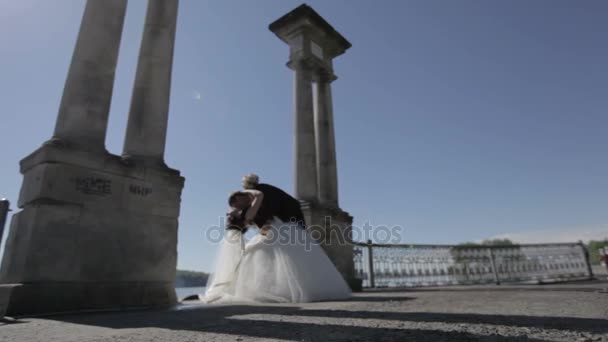 Bruidegom bruid kussen in de buurt van blue lake — Stockvideo