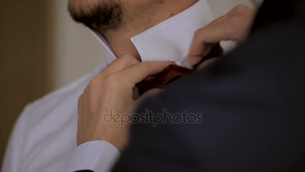 Чоловік кріпиться краватка на сорочці нареченого — стокове відео