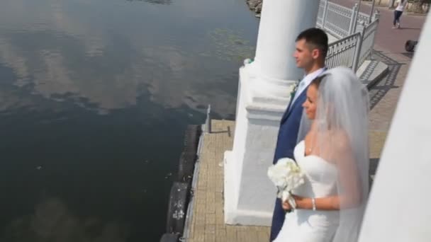 Frischvermähltes Paar steht am blauen See — Stockvideo