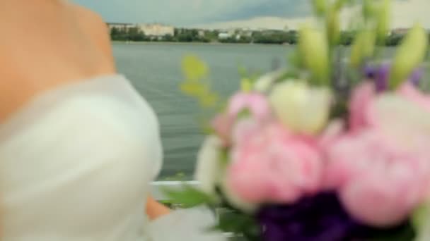 Όμορφη νύφη με μια γαμήλια ανθοδέσμη σε φόντο μπλε λίμνη — Αρχείο Βίντεο