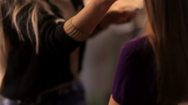 Flickan sitter i salongen av make-up artist och hon gör fashionabla make-up. — Stockvideo