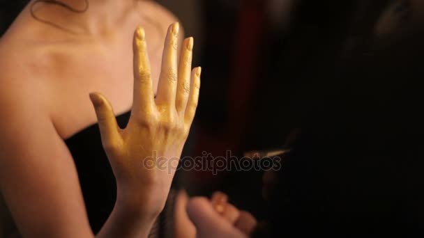 La fille est assise dans un studio d'art, le maître peint son pinceau. Le maître dans le salon d'art crée une image du modèle pour le podium. partie du corps — Video