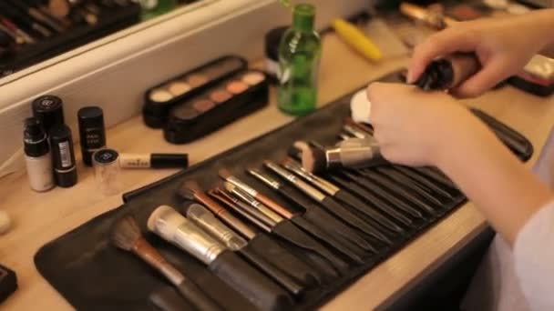 Professionelle Kosmetik Make-up auf dem Tisch im Studio. Bunter Lippenstift, Schatten, eine Basis für ein Make-up. professionelle Make-up-Pinsel in einer Ledertasche. Verwendung einer Make-up-Palette mit Pinsel — Stockvideo