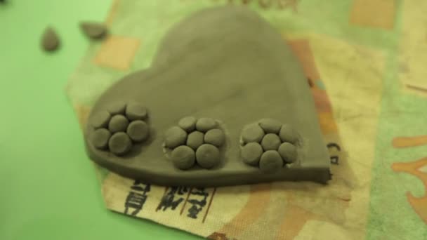 Виготовлення сувенірів з глини в художній майстерні. Глиняне серце на столі в художній майстерні . — стокове відео